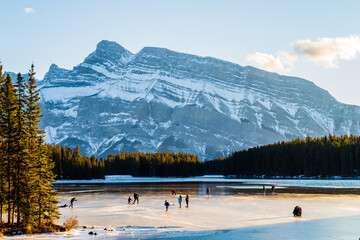 Beautiful view of people ice-skating on the Two Jack Lake in Banff national park, Canada