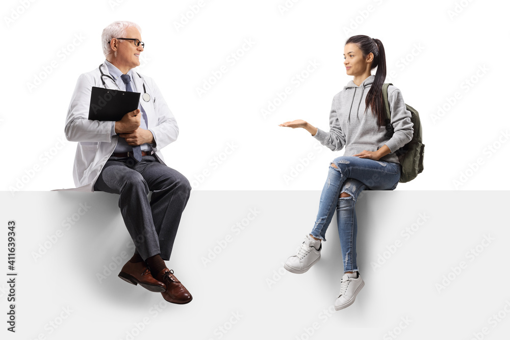 Wall mural full length shot of a female student talking to a mature doctor and sitting on a blank panel