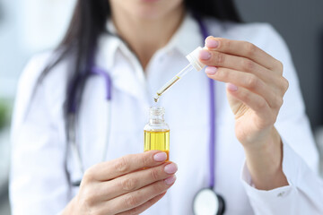 Doctor holds bottle with yellow liquid and pipette