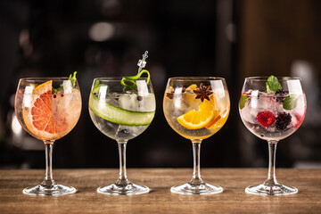 Gin tonic long drink as a classic cocktail in various forms with garnish in individual glasses such as orange, grapefruit, cucumber or berries - obrazy, fototapety, plakaty