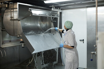 Portrait of female worker washing curdling machine in workshop at cheesemaking factory, copy space