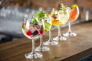 Gin tonic long drink as a classic cocktail in various forms with garnish in individual glasses such as orange, lemon, grapefruit, cucumber or berries