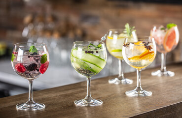 Gin tonic long drink as a classic cocktail in various forms with garnish in individual glasses such as orange, lemon, grapefruit, cucumber or berries