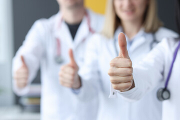 Three doctors stand behind each other and hold their thumbs up