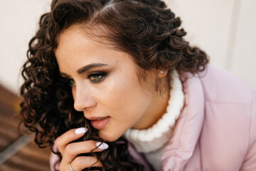 Beautiful girl turned in profile to the camera with bright stylish make-up thoughtfully brought beautiful hands with a delicate manicure to the lips. High quality photo