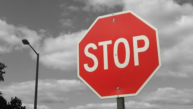Red and white stop sign with black and white background. Time lapse clouds. 