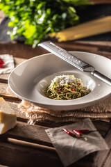 Spaghetti aglio e olio with olive oil, gralic, basil, parmesan cheese, tomatoes and chillies served in a deep plate