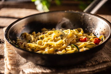 Vegetarian tagliatelle with zucchini and tomatoes served in sizzling hot pan