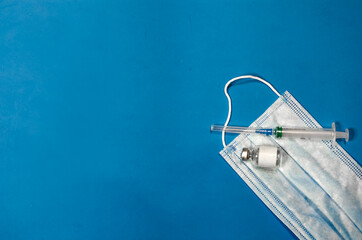 mask  vaccine and syringe on a blue background