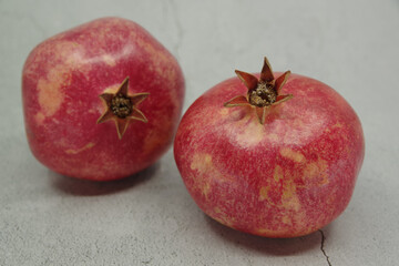 Ripe red pomegranates fruits on a grey background. Seasonal fruits. Royal fruit. Selective focus.