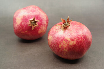 Ripe red pomegranates fruits on a brown background. Seasonal fruits. Royal fruit. Selective focus.