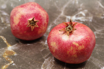 Ripe red pomegranates fruits on a brown background. Seasonal fruits. Royal fruit. Selective focus.