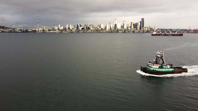 A tugboat cruises along the Puget Sound in Washington State with the city of Seattle, Washington in the background.