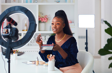 beautiful young african american woman streaming a beauty vlog from home, online content creator applying a makeup on - Powered by Adobe