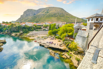 View of the Neretva River and tourists on the shore from atop the old Mostar Bridge in Mostar...