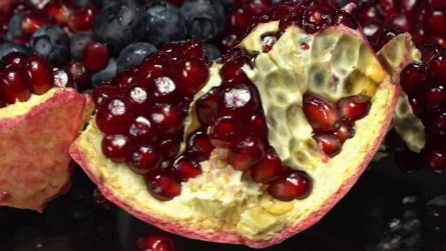 Pomegranate seeds and blueberries close up on a rotating surface