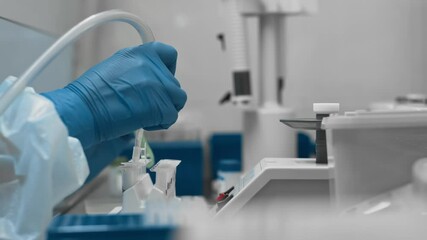 Scientist in protective suit and gloves performs chemical analysis of biological samples. Lab worker uses pipette and test tubes to research covid 19 virus - Powered by Adobe