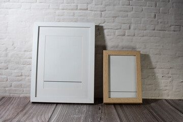 Dos marcos de fotografía en blanco sobre una pared de ladrillos.