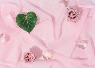 Pink rose flowers in water with silk fabric. Valentines or woman's day background design. Minimal flat lay nature.