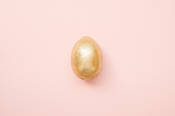 Easter golden glitter egg on pastel pink background. Minimal Easter concept. Happy Easter card with copy space for text. Top view, flat lay