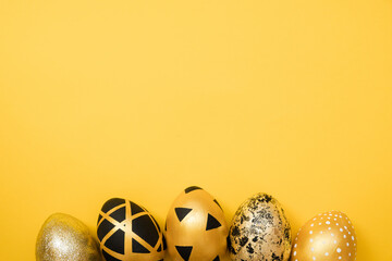 Easter golden decorated eggs on yellow background. Minimal easter concept. Happy Easter card with copy space for text. Top view, flatlay