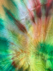 A closeup texture of a  green, yellow, brown, and orange cotton tye-dye t-shirt