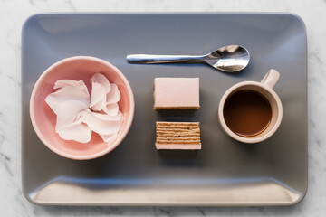Pink cake, coffee and petals on grey background