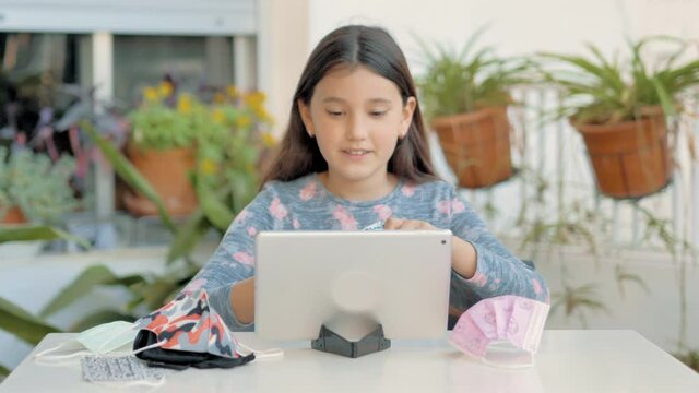 Ni&ntilde;a de pelo largo coqueta ense&ntilde;ando en videoconferencia varios tipos de mascarillas faciales