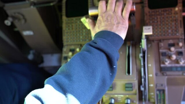 Close up, overhead view of an adult male hand advancing and retarding the throttle handles on a commercial airplane.