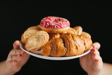 Diet. Hands holding plate with unhealthy sweets