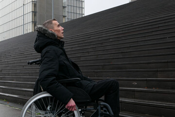 Fototapeta na wymiar Concept of disabled person. Man in a wheelchair outside in the street in front of stairs. 