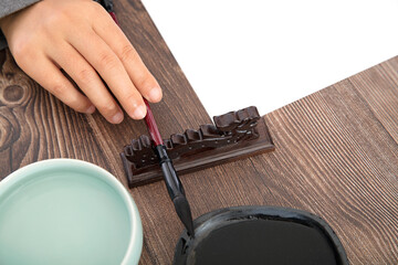 The calligrapher is about to pick up the brush on the holder and the inkstone and brush washer...
