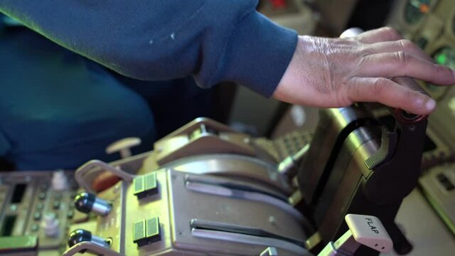 Side view, close up of an adult male hand advancing and retarding the throttle handles on a commercial airplane.