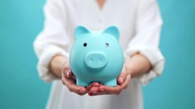 Hand holding blue piggy and saving money is an investment.