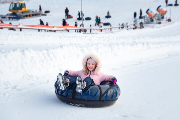 Fototapeta na wymiar a little girl rides a tubing down a slide