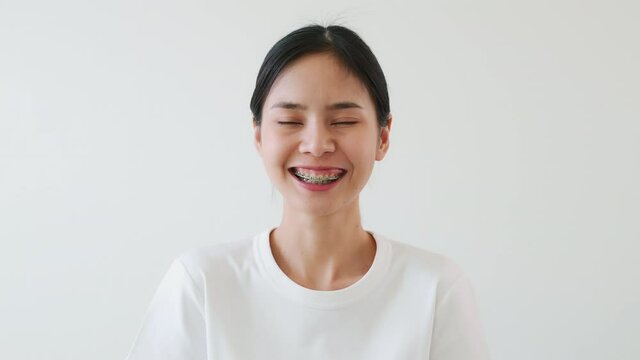 Asian women slowly smiled and laughed happily. A girl wearing braces.