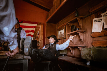 Cowboys group under taking in saloon bar at village ,they showing gun weapon on hand to protect from rob man.