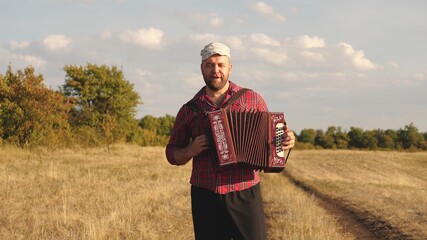 Man plays accordion in sun. Artist performs in open air, sings and plays musical instrument....