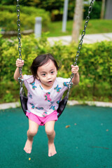 Active little toddler child playing swing at the playground. Happy and fun time.