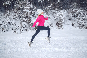 A woman runs in the snow in the winter mountains. Sports, fitness - inspiration and motivation. Woman jogging outdoors. High quality photo.