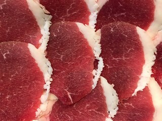 Raw beef meat slice on a plate ready to serve. Beef meet top view closed up.