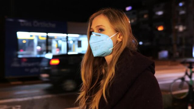 [4k] portrait of young woman in ffp2 face mask walking big city street at night