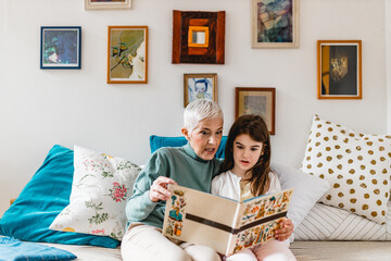 Grandmother and granddaughter having fun together and reading a book at home