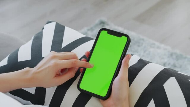 Close up of woman holding in hands a mock up smartphone with green screen for internet online, chromakey screen for advertising.