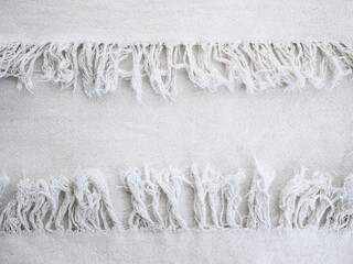 Close up beige cotton fabric texture with fringe edge.