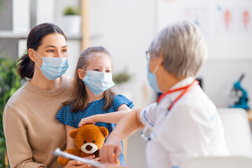 Doctor, child and mother wearing facemasks