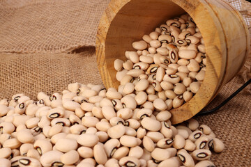 Blackeye beans in wooden small bucket on jute yarn fabric background