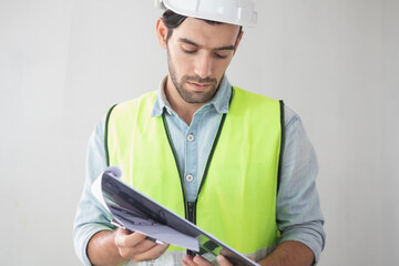 Smart young caucasian man contractor, partner holding, looking at paperwork on the clipboard,inspecting the reconstructed construction and renovation after to check defect of apartment,home at site