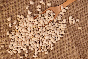 Blackeye beans in wooden scoop spoon jute yarn fabric background
