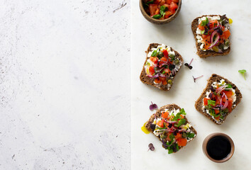 Open face rye bread sandwiches with soft cheese, tomatoes, red onions and capers
